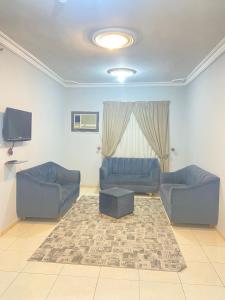 a living room with two blue couches and a tv at أجــنــحــة وتــيــن in Al Madinah