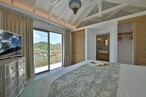 a bedroom with a large bed and a large window at Villa Vogue 5 Bedroom Villa in Saint Barthelemy