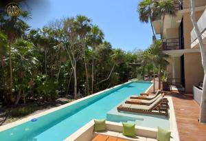 ein Swimmingpool mit Liegestühlen und Palmen in der Unterkunft Penthouse Privado en Tulum in Tulum