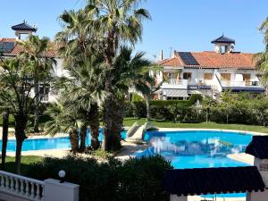 uma vista para uma piscina de resort com palmeiras em Parquemar em La Mata