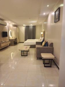une chambre d'hôtel avec un lit, un canapé et des tables dans l'établissement Blend Hotel, à Dammam