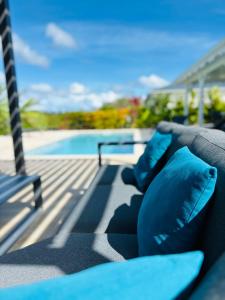 a couch with blue pillows sitting next to a swimming pool at Villa Diamond in Sainte-Luce