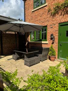 a patio with two chairs and an umbrella at Piper Cottage, Bilbrough, York in Bilbrough