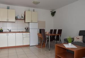 eine Küche mit weißen Schränken und einem Tisch mit Stühlen in der Unterkunft Apartmani Andrea in Čižići