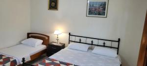 ein Schlafzimmer mit 2 Betten und einer Lampe auf einem Tisch in der Unterkunft Guesthouse Reçka in Gjirokastër