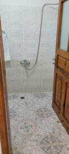 ein Bad mit einer Dusche mit einer Tür und Fliesenboden in der Unterkunft Guesthouse Reçka in Gjirokastër