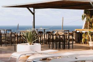 a patio with tables and chairs and a view of the ocean at The Tree House Tenerife in El Médano