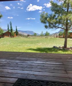 a wooden deck with a tree in a field at Yellowstone Cutthroat Guest Ranch in Wapiti