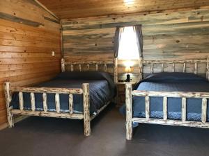two beds in a room with wooden walls at Yellowstone Cutthroat Guest Ranch in Wapiti