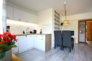 a kitchen with white cabinets and a table and chairs at Las i Woda in Lubin