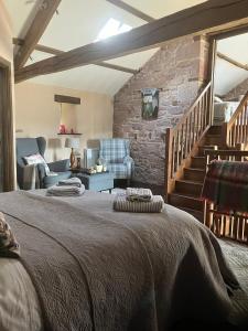 a bedroom with a bed and a stone wall at Historic converted byre in courtyard of 16C house in Caldbeck