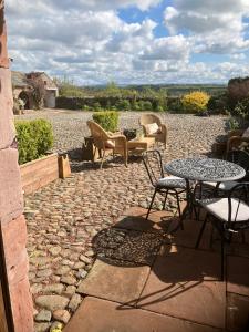 a stone patio with chairs and a table and chairs at Historic converted byre in courtyard of 16C house in Caldbeck