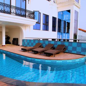 a swimming pool with chairs next to a building at SALA HOTEL HUE in Hue