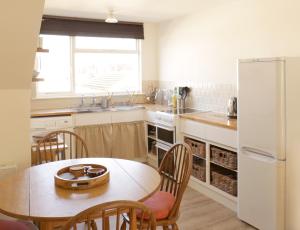 cocina con mesa, sillas y nevera en Sunny Seaside Sanctuary - Two Bedroom Apartment en Brighton & Hove