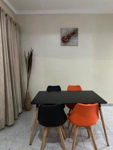 a dining room with a black table and four chairs at Well furnished and very spacious apartment in Wuye in Abuja