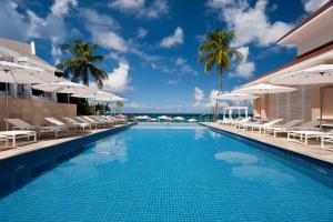 einen Pool mit Stühlen und Sonnenschirmen in einem Resort in der Unterkunft BodyHoliday St Lucia in Gros Islet