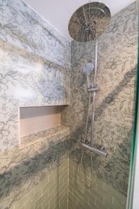 um chuveiro na casa de banho com papel de parede floral em Appartement rénové Proche Paris - 5 min transport em Montrouge