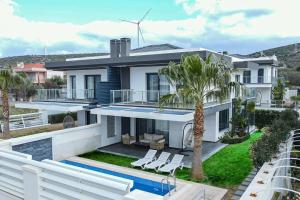 a white house with a pool and palm trees at Çeşme lüks huzurlu yeni villa in Çeşme