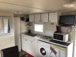 a small kitchen with a washing machine and a microwave at Mobilhome à Fréjus à 15 minute de la mer sur terrain indépendant in Fréjus