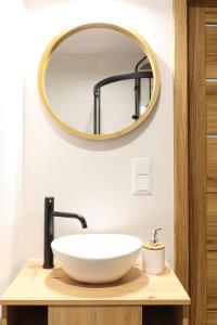 W łazience znajduje się biała umywalka i lustro. w obiekcie Strumienna Apartament w Krakowie