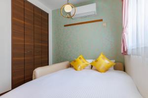 Un dormitorio con una cama con almohadas amarillas. en Tsubaki house, en Yomitan 40 fotos más