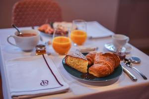 una mesa con un plato de cruasanes y zumo de naranja en Hôtel Château - Domaine de Coeurmandie en Bény-sur-Mer