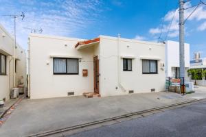 un edificio blanco con ventanas negras en una calle en Tsubaki house, en Yomitan