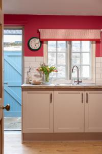 uma cozinha com um lavatório e um relógio na parede em Lightfoot Cottage em Bishop Auckland