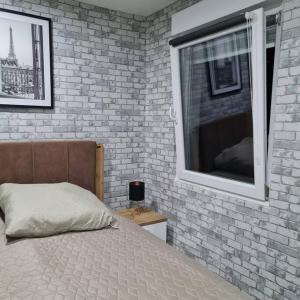 um quarto com uma parede de tijolos, uma cama e uma janela em Elias Ruheoase em Pfungstadt