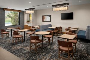 a waiting room with tables and chairs and a flat screen tv at Hyatt Place Denver Cherry Creek in Denver