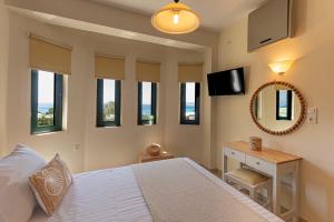 a bedroom with a bed and a television and windows at Terra Calma Residence in Karistos
