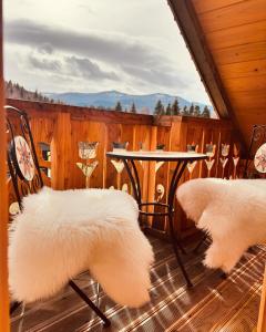 a porch with two chairs and a table and a fence at Oskarówka domek w górach na odludziu z jacuzzi i sauną - kominek i Netflix in Szczawa