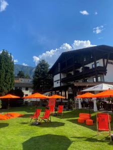 um grupo de cadeiras e guarda-sóis laranja em frente a um edifício em Gasthof Schlossberghof em Lienz