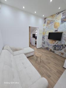 a living room with a white couch and a tv at IDILA SPA in Novi Beograd