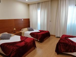 a hotel room with two beds with red sheets at Colina do Ave Alojamento Local in Ribeirão