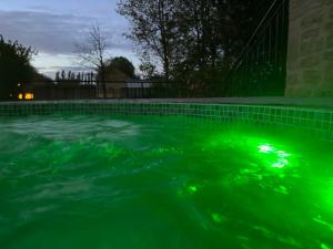 una piscina con luces verdes en el agua en Hôtel Château - Domaine de Coeurmandie en Bény-sur-Mer