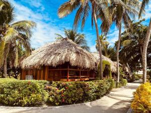 un complejo con palmeras y una cabaña de paja en St. George's Caye Resort, en Ciudad de Belice