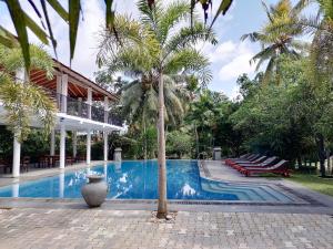 a pool with a palm tree next to a house at Seetharama Garden of Life in Beruwala