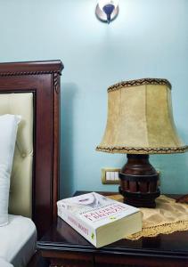 lampa i książka na stole obok łóżka w obiekcie Villa Parku Rinia w mieście Korcza
