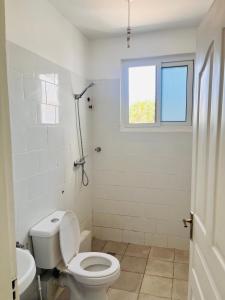 a white bathroom with a toilet and a window at Bharazah Luxury Apartment in Malindi