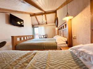 a bedroom with two beds and a flat screen tv at VinoOdor - ვინოოდორ in Tʼelavi