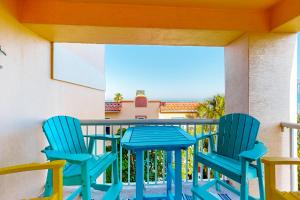 un patio con sillas azules y una mesa en el balcón en Sunset Sea Villa en Clearwater Beach