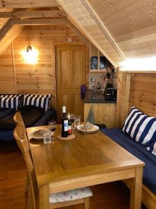 Cette chambre en bois comprend une table et un canapé. dans l'établissement Holly Tree Glamping Cabins, à Wigglesworth