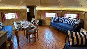 - un salon avec un canapé bleu et une table dans l'établissement Holly Tree Glamping Cabins, à Wigglesworth