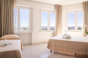 um quarto de hotel com duas camas e janelas em Hotel De Plam em Olbia