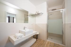 a white bathroom with a sink and a shower at Suimi's Hotel in Villasimius