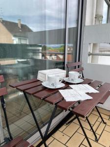 a table with two cups and a microwave on a balcony at Schirmeck Apartment in Strasbourg