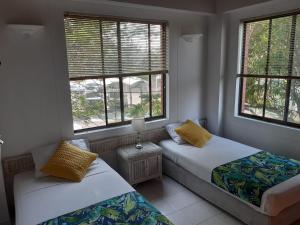duas camas num quarto com duas janelas em Apartamento Condominio Girardot Resort Apto 6-402 Vista a las montañas ,WI-FI- RNT # 96655 em Girardot