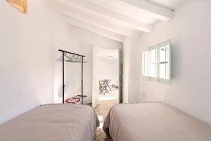 2 Betten in einem weißen Zimmer mit Fenster in der Unterkunft El Patio de Rafaela in El Cerro