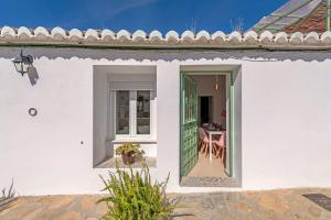 ein weißes Haus mit einer grünen Tür und einem Tisch in der Unterkunft El Patio de Rafaela in El Cerro
